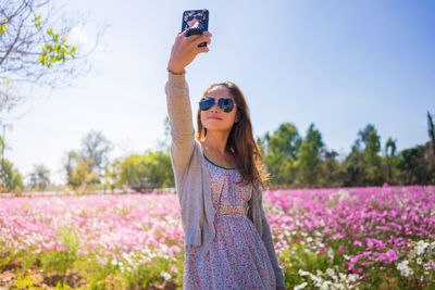 Woman wearing sunglasses taking selfie while standing on land