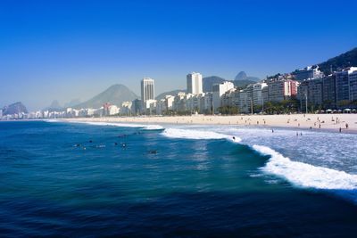 View of sea and buildings against clear blue sky