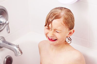 High angle view of boy making face while bathing in tub