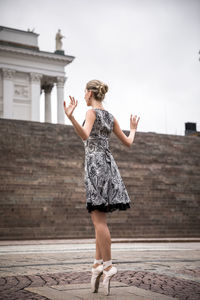 Full length of female ballet dancer dancing against staircase in city