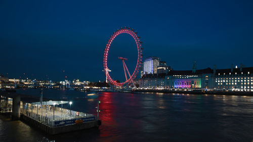 Illuminated ferris wheel in city at night