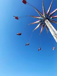 Low angle view of chain swing ride against clear blue sky