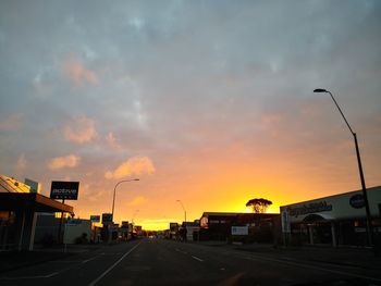 Cars on street against sky at sunset