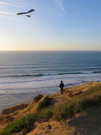 Rear view of woman standing against sea at beach