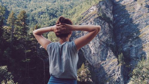 Rear view of young woman standing against mountain