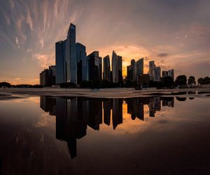 Reflection of buildings in lake against sky during sunset