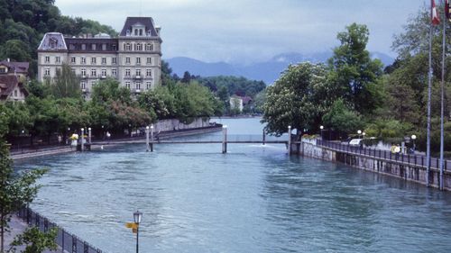 Scenic view of river by buildings against sky