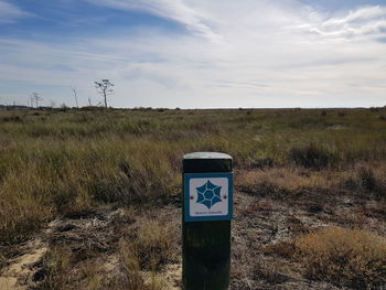 Information sign on field against sky