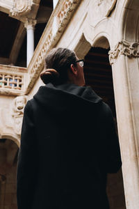 Rear view of woman standing against building