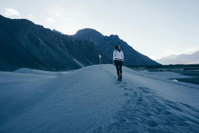 Rear view of woman walking on snow covered mountain