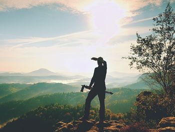 Man with arms raised on landscape against sky
