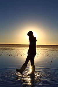 Silhouette man on beach against sky during sunset