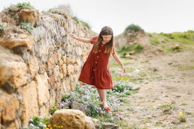 Full length of girl walking by stone wall