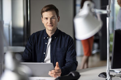 Confident young businessman using digital tablet while sitting at office