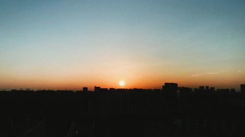 Silhouette buildings against sky during sunset