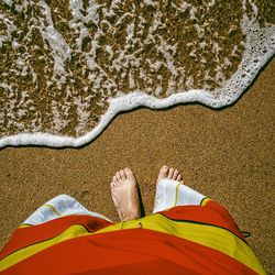 Low section of person lying on sand at beach