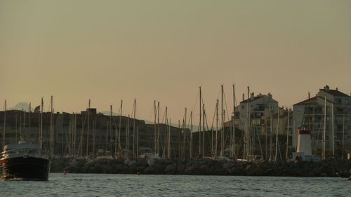 Boats moored at harbor against sky during sunset