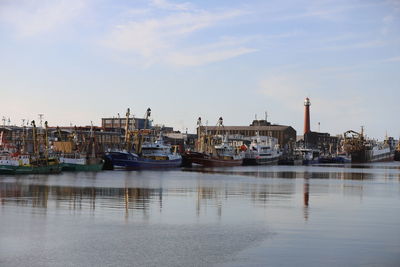 Sailboats moored at harbor against buildings in city