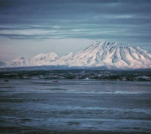 Scenic view of sea and snowcapped mountains against sky