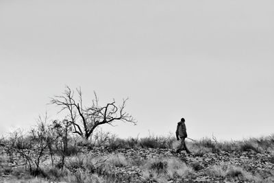 Rear view of man standing on field against clear sky