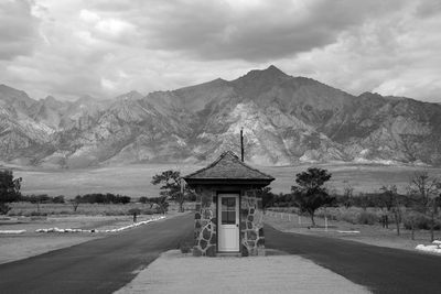 Guard shack at closed internment camp by mountains against clouds