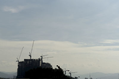 Cranes in construction site against sky