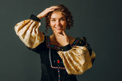 Portrait of young woman drinking milk while standing against black background