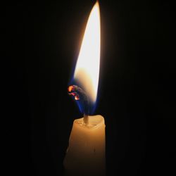 Close-up of illuminated candle in darkroom