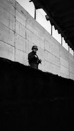 Solider with rifle standing against wall