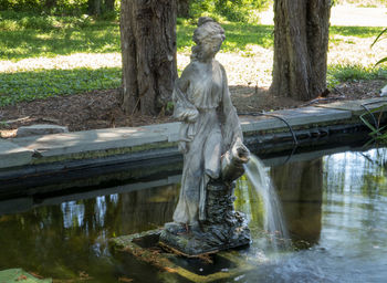 Statue by lake in park