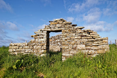 Old ruins of building on field against sky