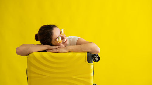 Woman holding yellow umbrella against orange background