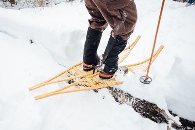 Low section of man snowshoeing on field