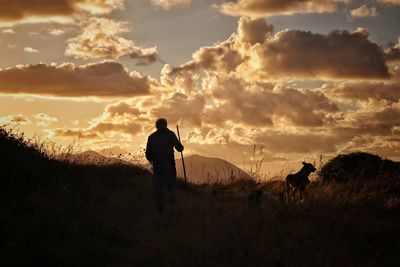 Men on field against sky during sunset