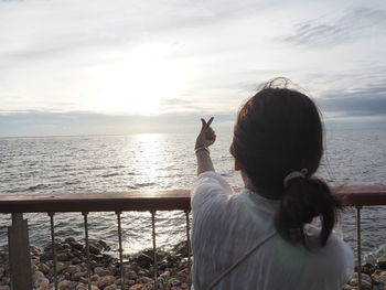 Rear view of woman on beach against sky