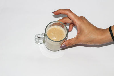 Midsection of person holding coffee cup against white background