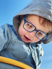 Portrait of toddler boy in eyeglasses against the blue sky