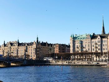 River by buildings against clear blue sky