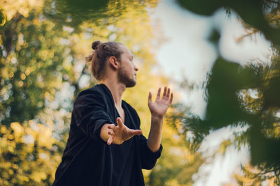 Young woman standing against trees