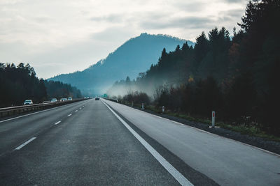 Road by trees against sky