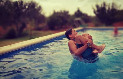 Shirtless boy jumping into pool