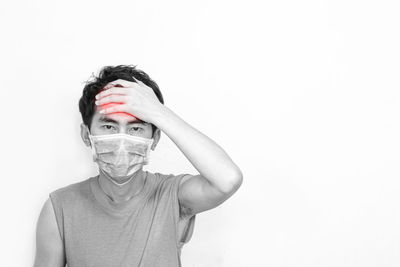 Portrait of man covering face against white background
