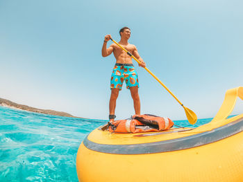 Man standing by sea against clear blue sky