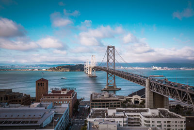 View of suspension bridge over sea against cloudy sky