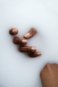 Dark skin hand in the milky smooth water substance