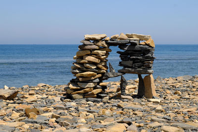 Stack of stones on beach against clear sky