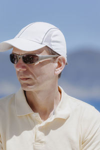 Mature man wearing sunglasses and cap against sky during sunny day