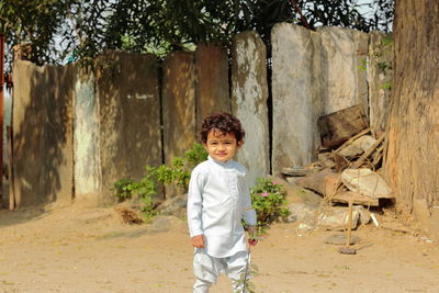 Portrait of boy standing against trees