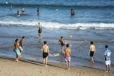 Rear view of people enjoying at beach