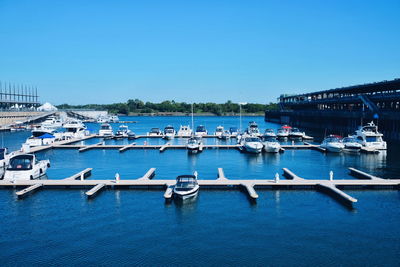 Sailboats moored in sea against clear blue sky